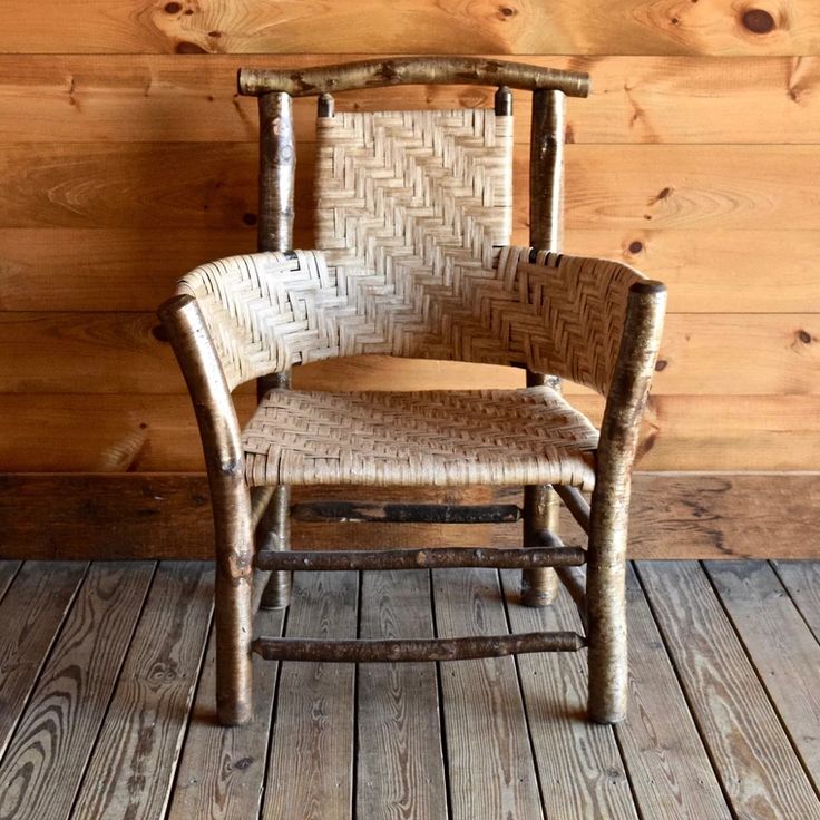 a wooden chair sitting on top of a hard wood floor next to a log wall