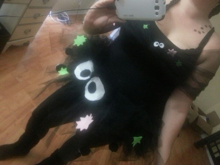 a woman taking a selfie with her cell phone while wearing a black dress that has green and white stars on it