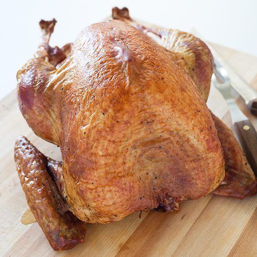 a whole chicken sitting on top of a wooden cutting board next to a pair of scissors