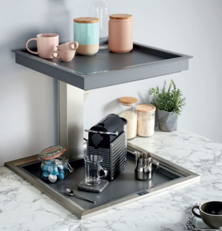 there is a coffee maker and cups on the tray in this kitchen counter top space