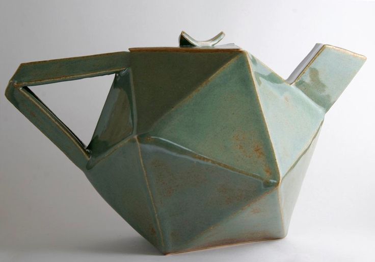 a ceramic teapot shaped like an origami bird sitting on it's side