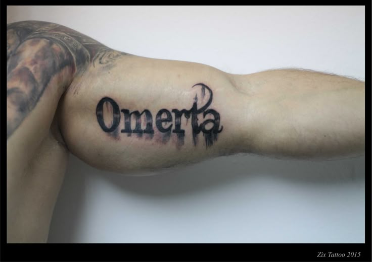 a man's arm with an omerta tattoo on the upper part of his arm