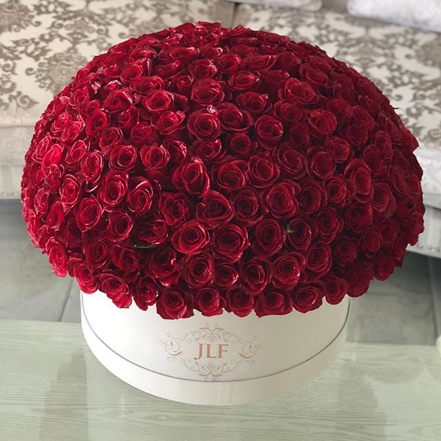 a white box filled with red roses on top of a table