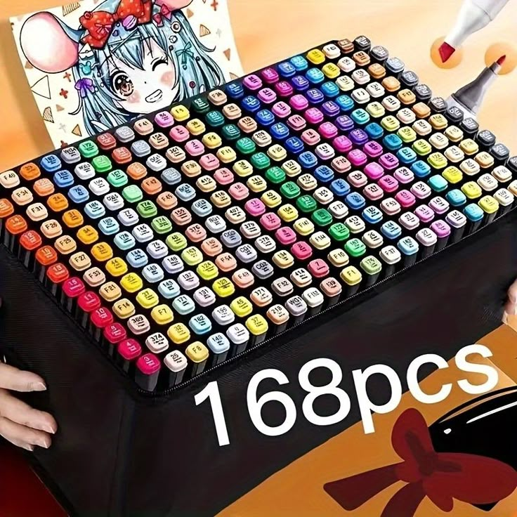 a person holding a large box filled with lots of colored crayons on top of a table