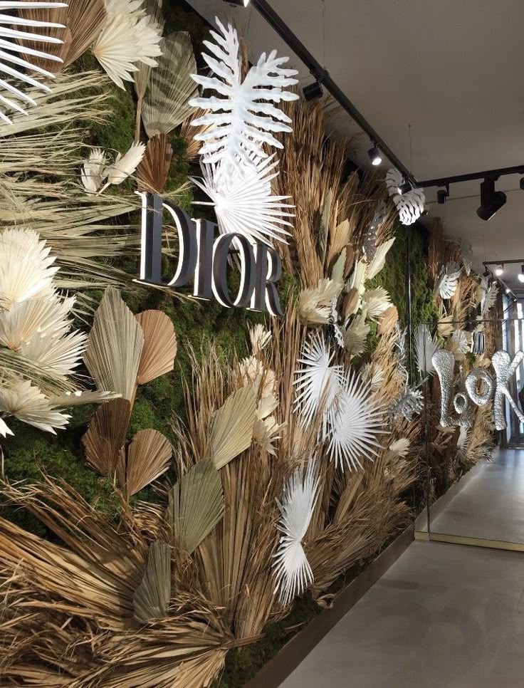 the wall is decorated with plants and flowers in white, green and gold colors that are part of dior's new showroom