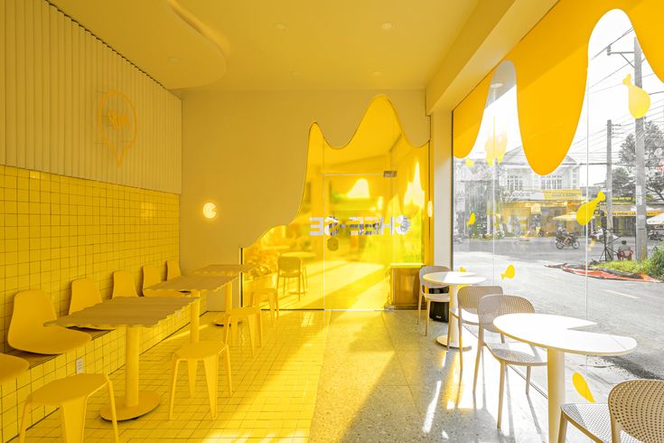 the interior of a restaurant with yellow tables and chairs