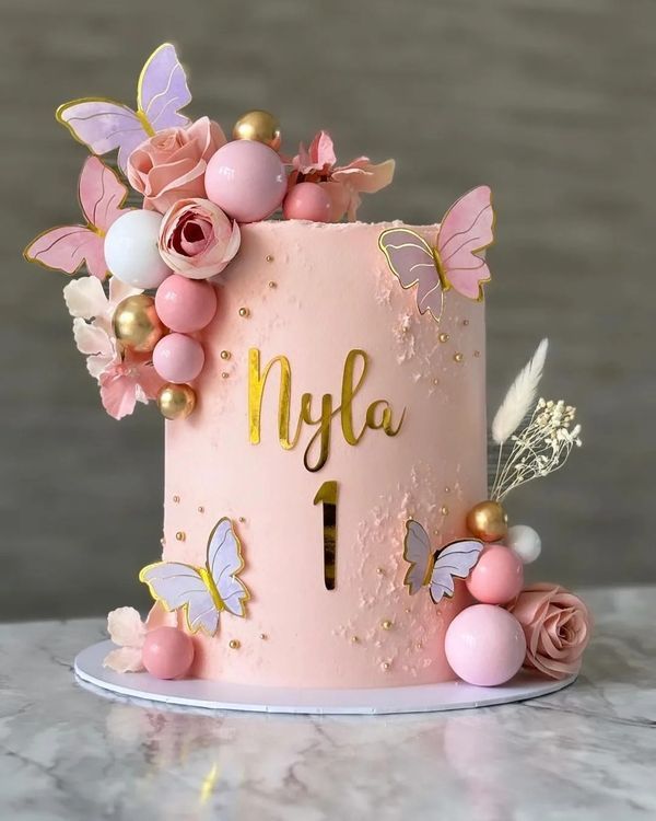 a pink cake decorated with flowers and butterflies