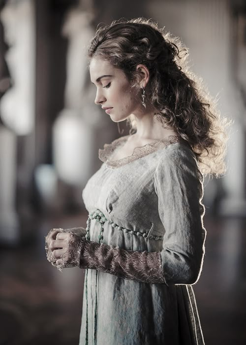 a woman with long hair wearing a green dress and holding her hand on her hip