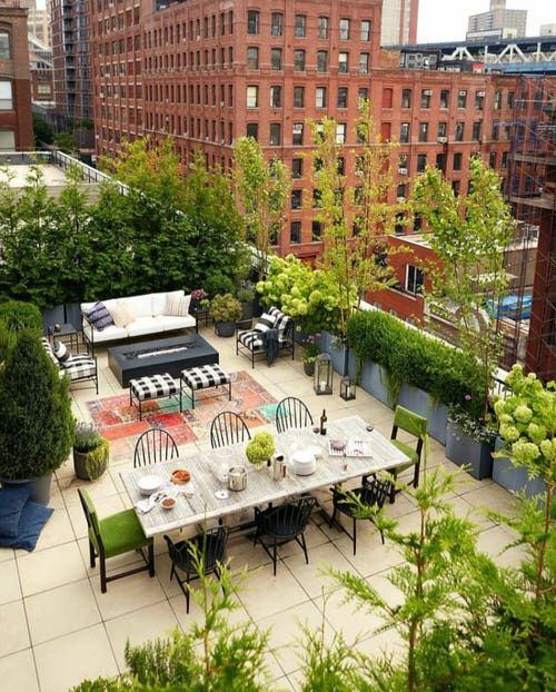 an outdoor dining area in the middle of a city with lots of trees and plants