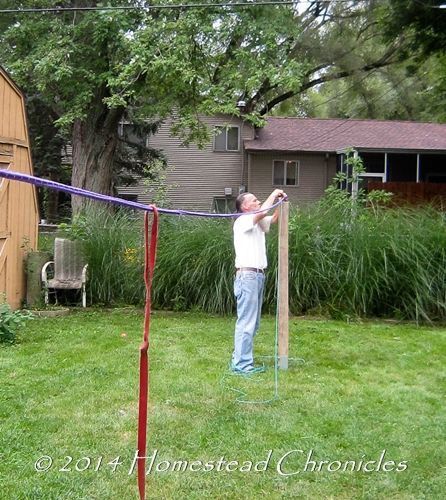 a man is playing volleyball in the yard with a net on his back and two poles attached to it