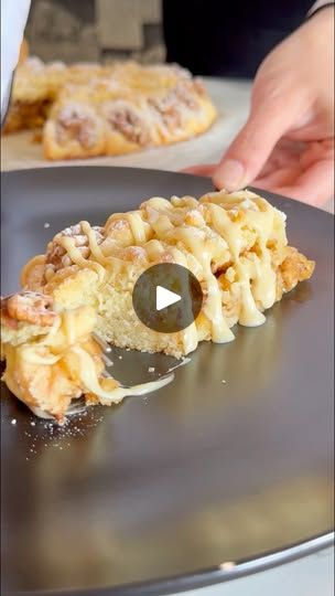 a person cutting up food on top of a black plate next to another piece of pizza