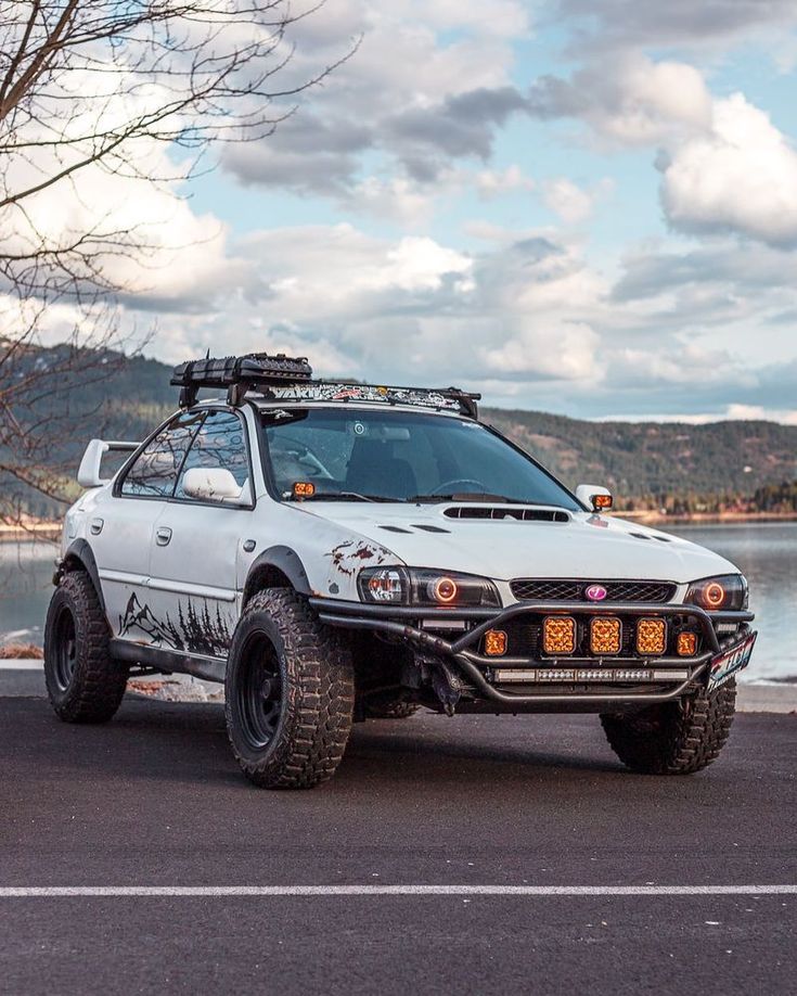 an off - road vehicle is parked on the side of the road near some water