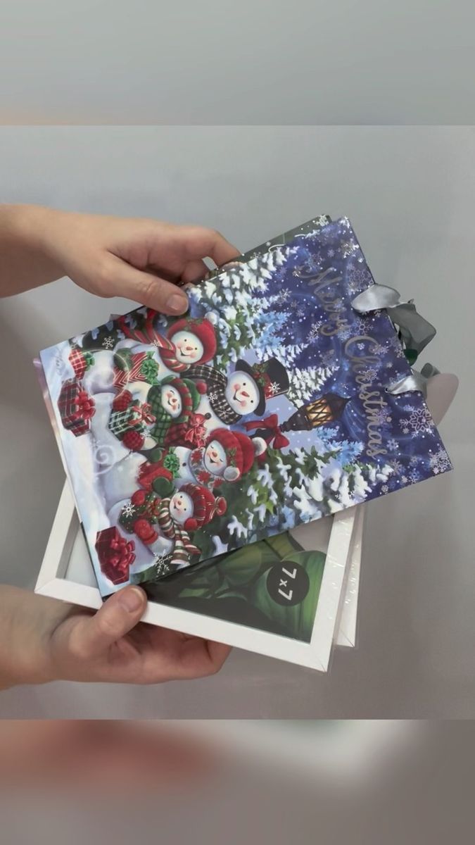 two hands holding christmas cards on top of each other