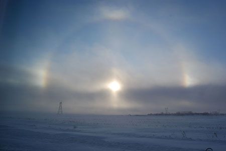 two rainbows are seen in the sky over a snow covered field