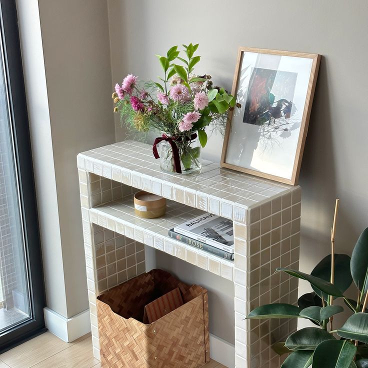 a vase with flowers sitting on top of a white table next to a planter