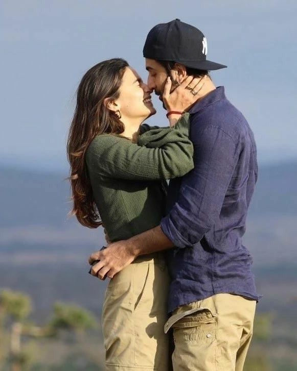 a man and woman standing next to each other with mountains in the back ground behind them