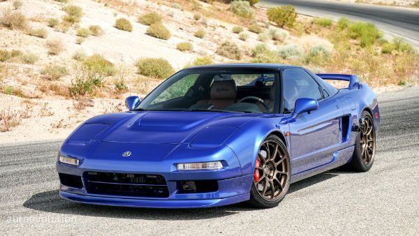 a blue sports car parked on the side of a road next to a desert area