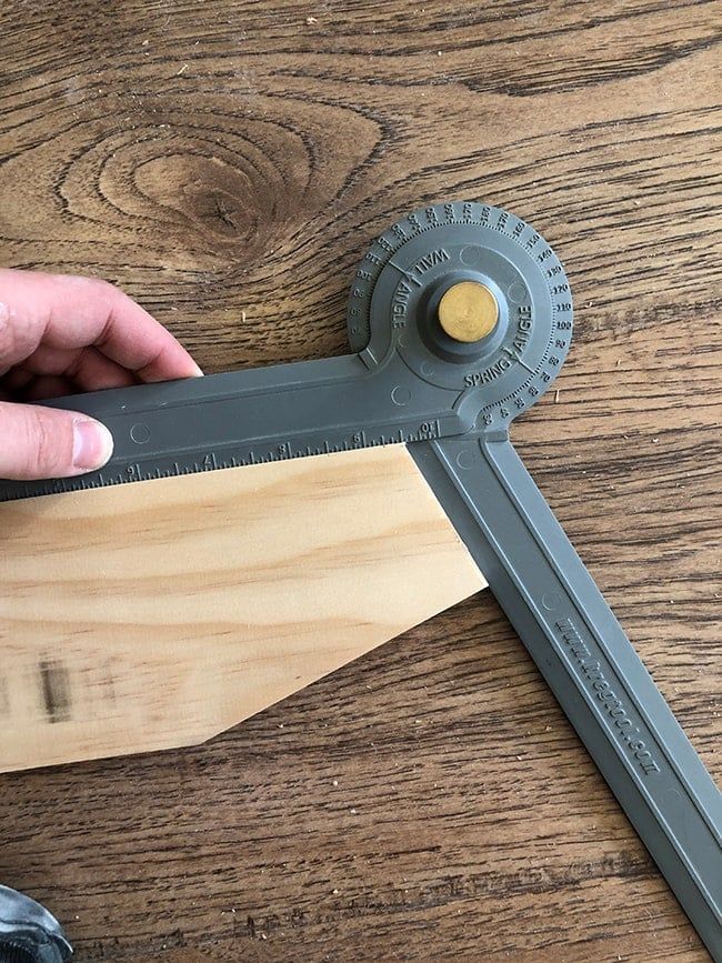 a person holding a large metal ruler on top of a wooden table