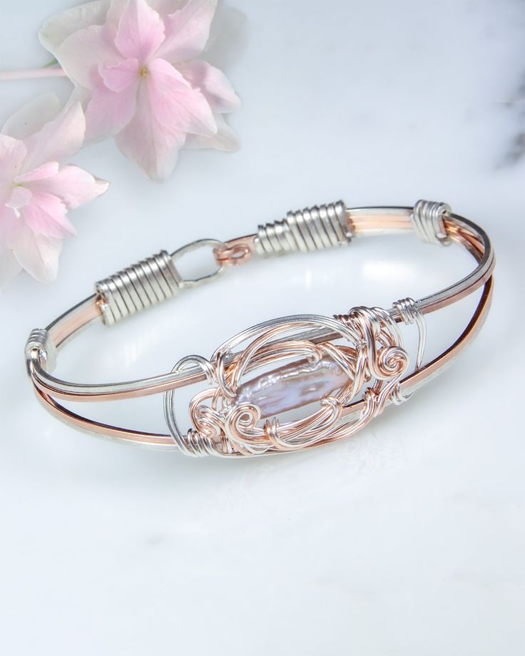 “This design is Inspired by the gentle curls of swirling water, I designed sterling silver and rose gold-filled wire to complement the lovely soft pink pearl. Over 8 feet of wire is used to create the bracelet." -Laura Glen Freshwater Pearl Gently squeeze the bracelet sides to open and close Handmade with subtle design variations Each pearl is unique, with subtle variations Twist Jewelry, Wire Jewelry Patterns, Wire Bangles, Freshwater Pearl Bracelet, Wire Wrapped Bracelet, Diy Wire Jewelry, Hand Jewelry, Pink Pearl, Hand Made Jewelry