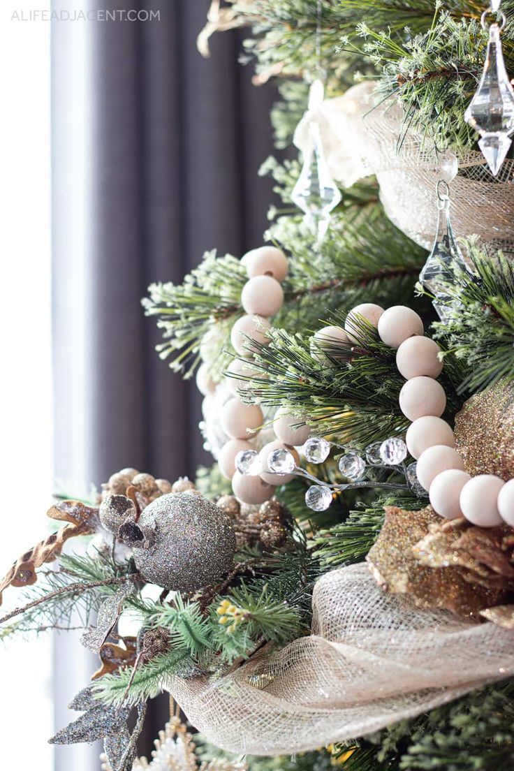 the christmas tree is decorated with gold and silver ornaments, pearls, and burlocks