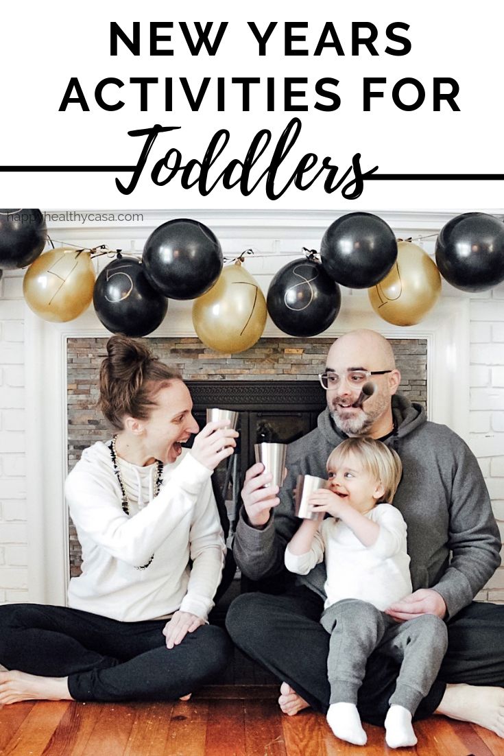 a family sitting on the floor in front of a fireplace with black and gold balloons