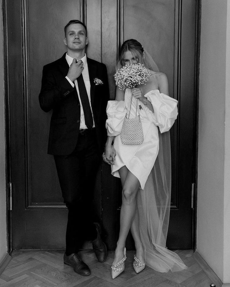 a man in a suit and tie standing next to a woman wearing a wedding dress