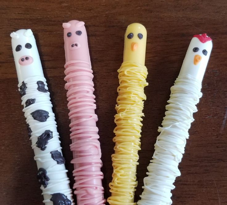 four different colored toothbrushes in the shape of farm animals and pigs, with faces drawn on them