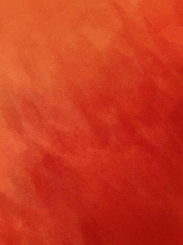 an orange and red background with some stains