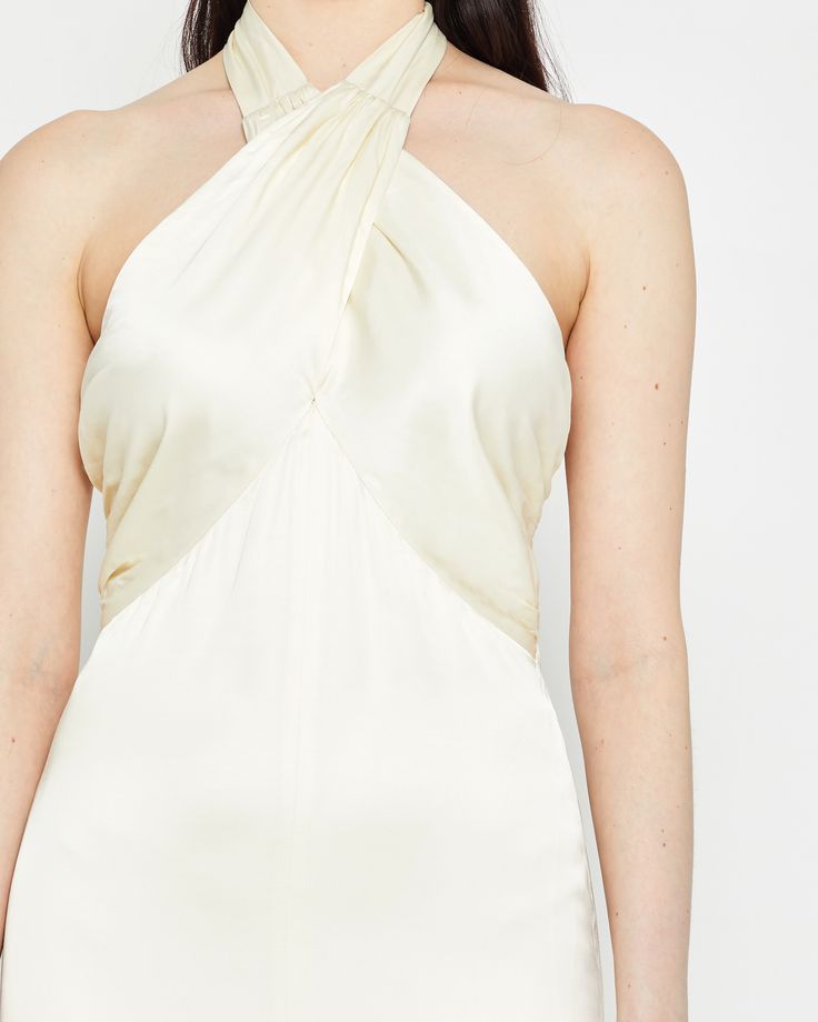 a woman wearing a white dress with an asymmetrical halter neckline