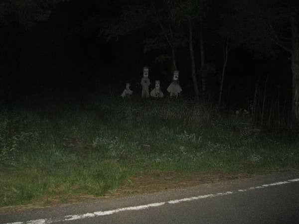 three people are sitting in the grass at night with their heads turned to look like they're dead