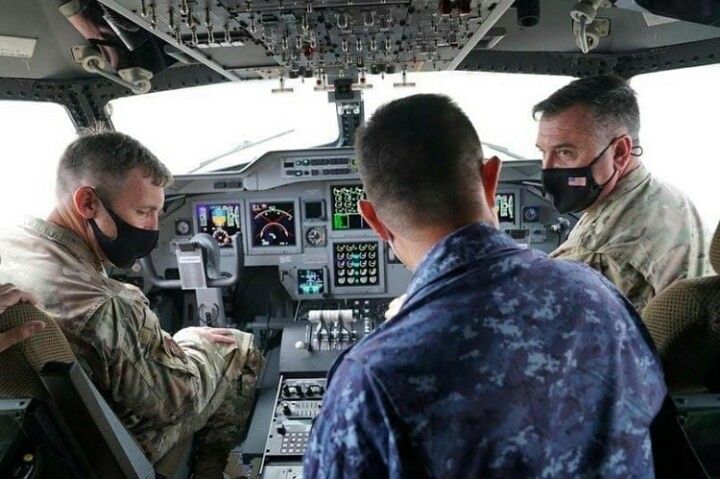 two pilots wearing face masks while sitting in the cockpit of an airplane, looking at each other