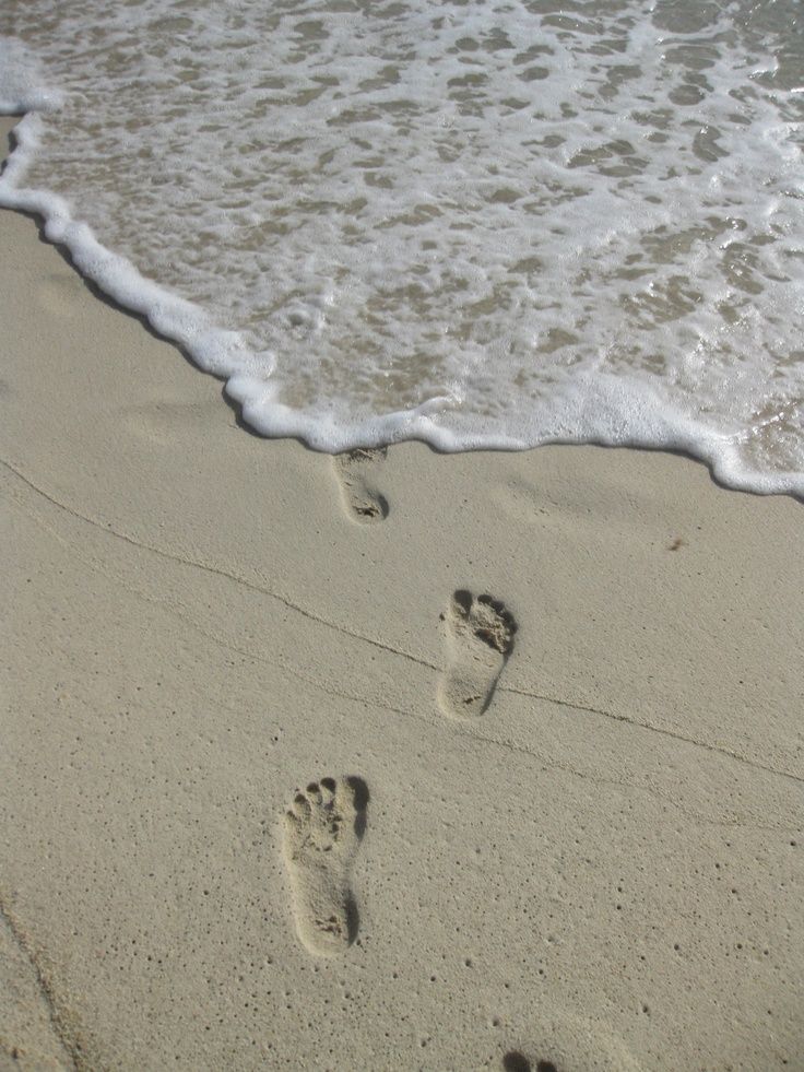 two footprints in the sand next to the ocean