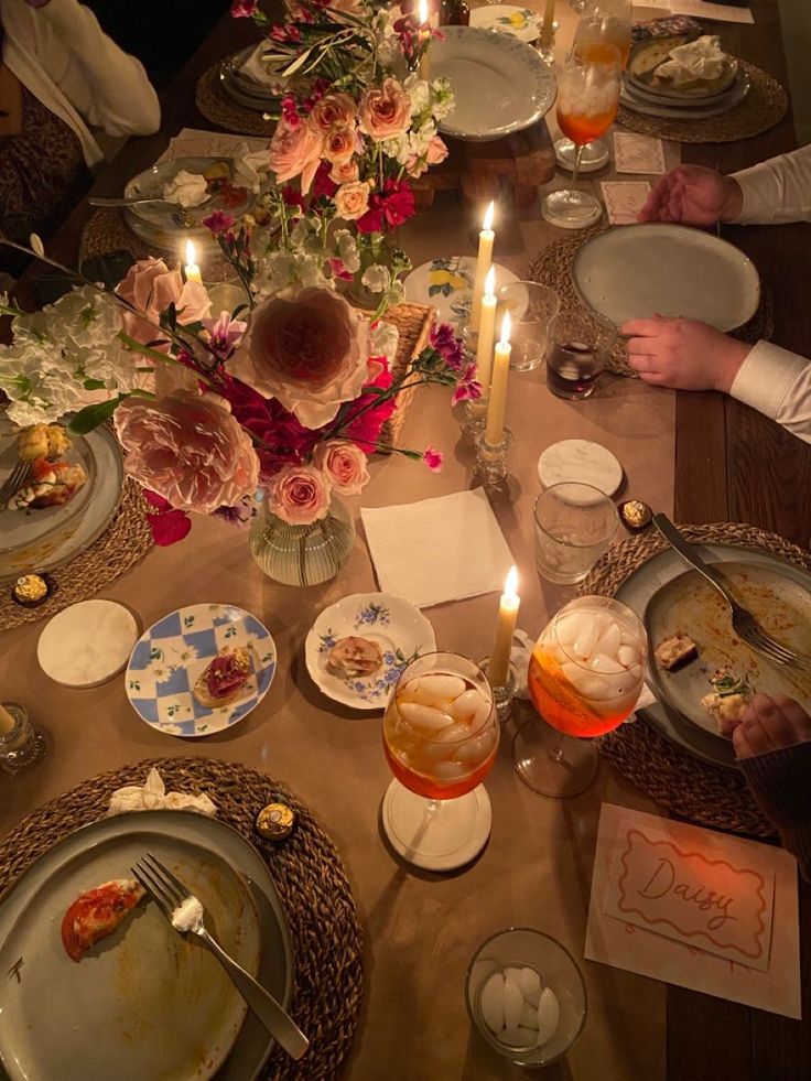 people sitting at a table with plates and candles