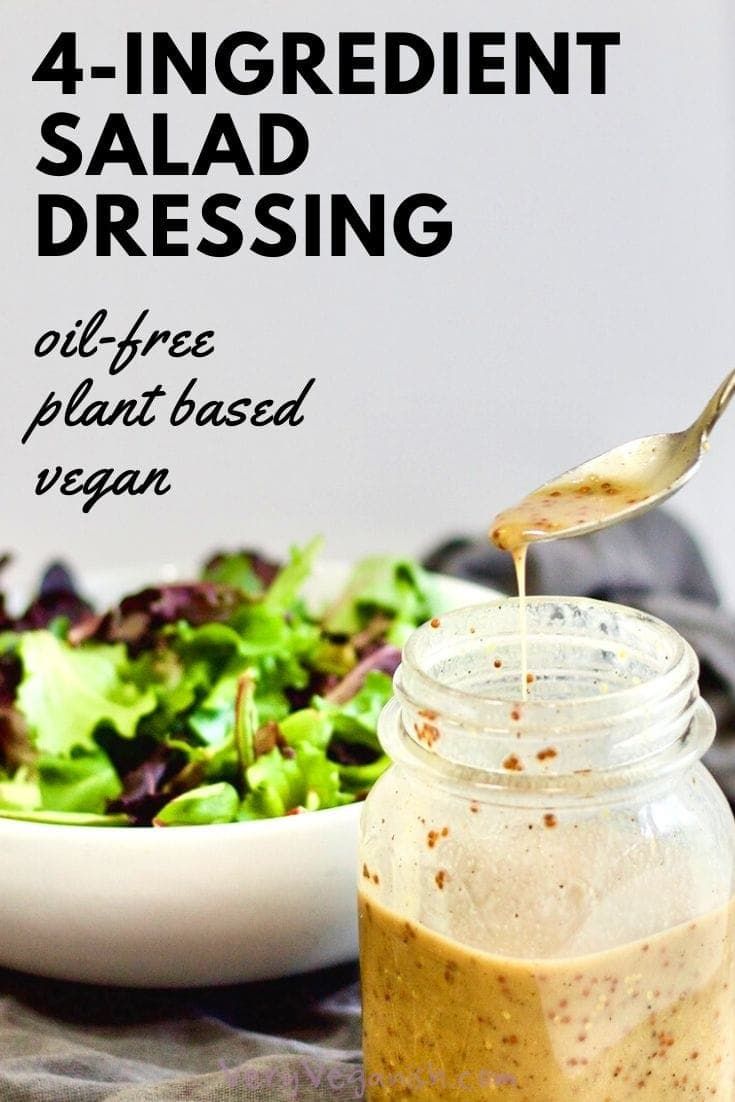 a salad dressing in a jar next to a bowl of salad