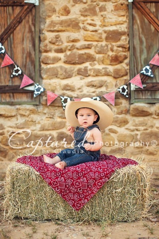 a baby wearing a cowboy hat sitting on hay