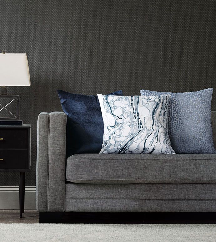 a gray couch with blue and white pillows on it next to a black night stand