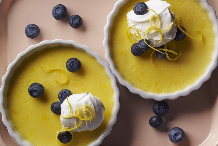 two desserts with blueberries and whipped cream on a pink tray next to each other