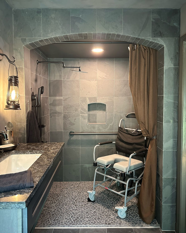 a bathroom with a shower, sink and chair in it's stall area next to the bathtub