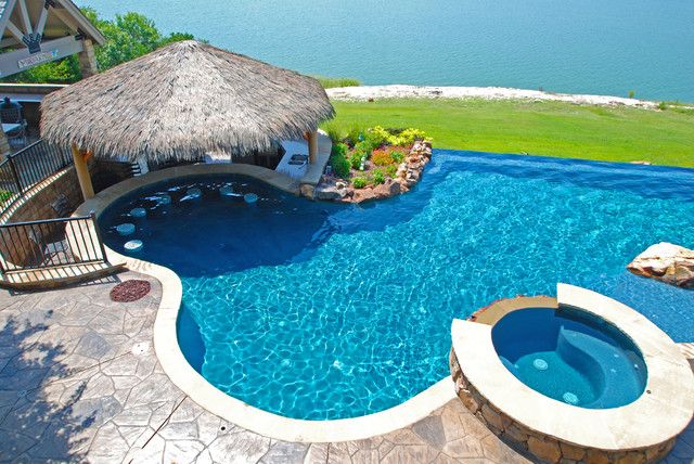 an outdoor swimming pool with a thatched roof