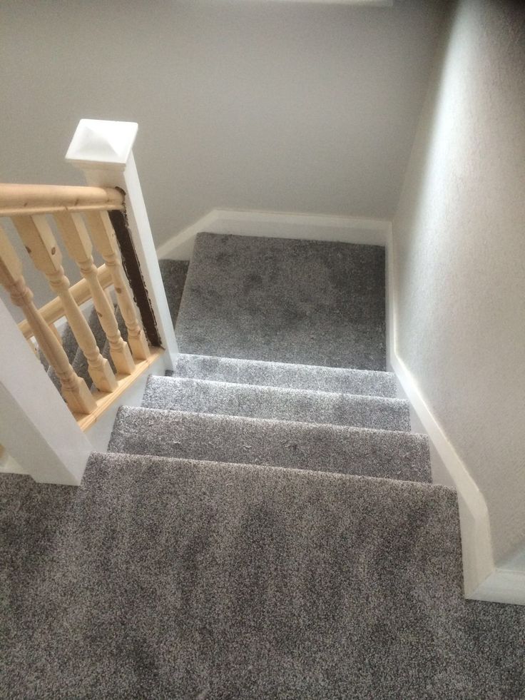 stairs leading up to the second floor in an empty room with carpeted floors and white walls