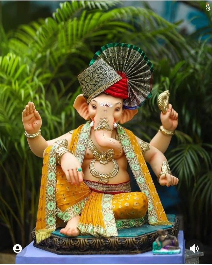 an elephant statue sitting on top of a blue table next to some green plants and trees