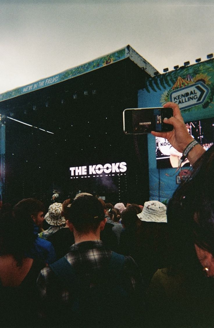 a group of people standing in front of a stage with a sign that says the kooks on it