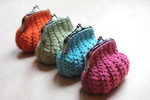 small crocheted purses are lined up on a white counter top, one is pink, the other is blue