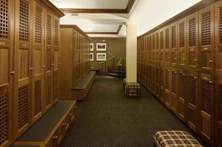 a long hallway with many wooden lockers lined up against the wall and benches on either side