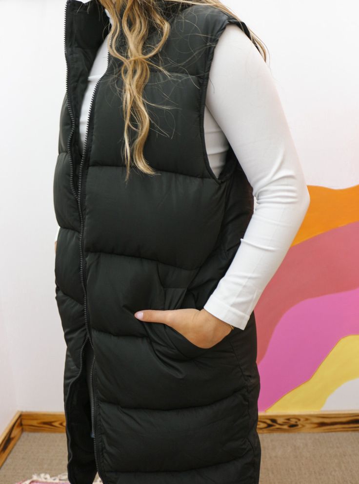 Stay warm and stylish with our Classy In The Cool Long Black Puffer Vest. Made from high-quality materials, this vest will keep you cozy throughout the cooler months. Its sleek and classic design will elevate any outfit, making it a must-have for your winter wardrobe. Embrace the cold in style and comfort with our Long Black Puffer Vest! Casual Cold Weather Outerwear Vest, Black Winter Vest With Pockets, Fitted Casual Vest For Cold Weather, Casual Black Winter Vest, Casual Solid Vest For Cold Weather, Black Winter Vest For Cold Weather, Black Vest For Cold Weather And Winter, Cold Weather Solid Puffer Vest, Solid Puffer Vest For Cold Weather