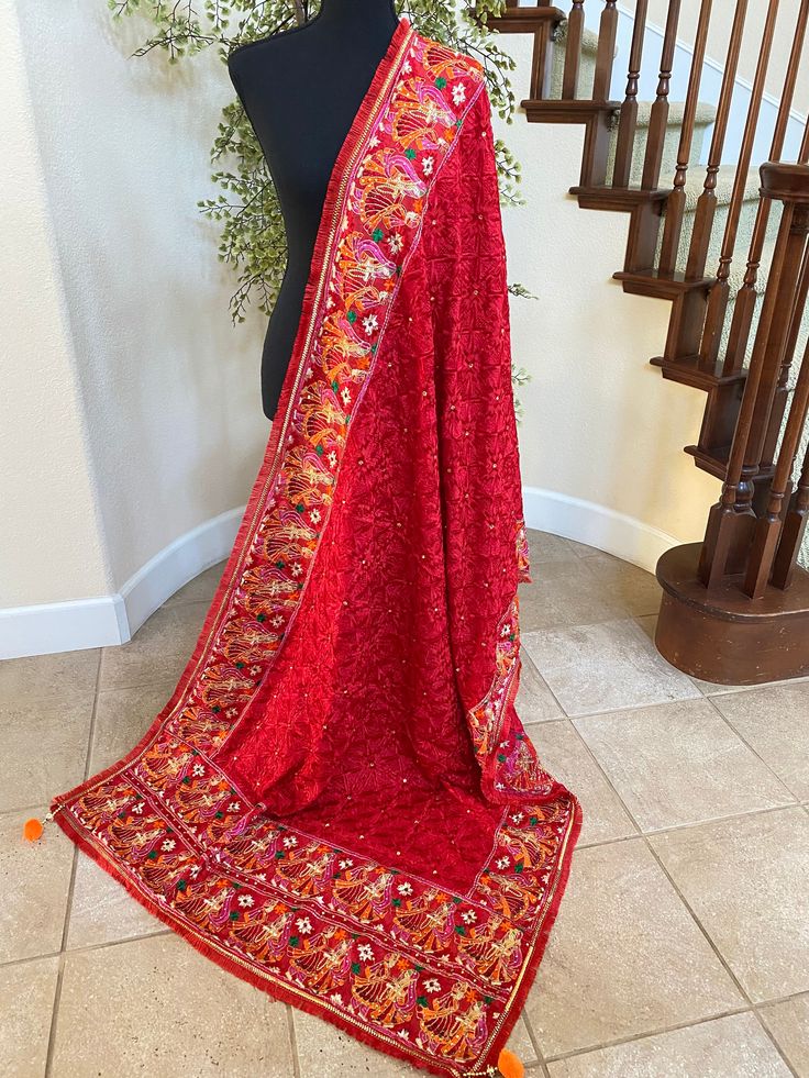 a red shawl draped over a mannequin in front of a stair case