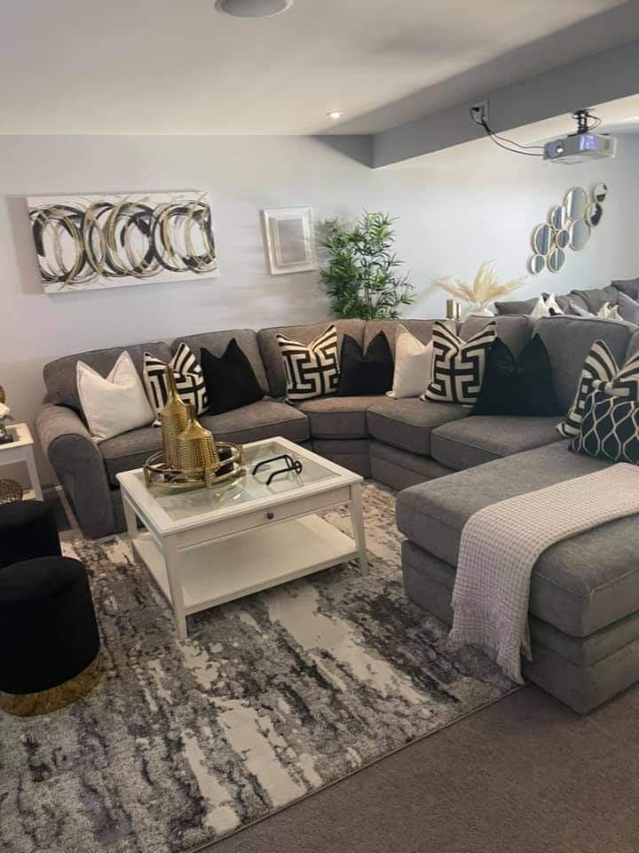 a living room with grey couches and black and white pillows on the rugs