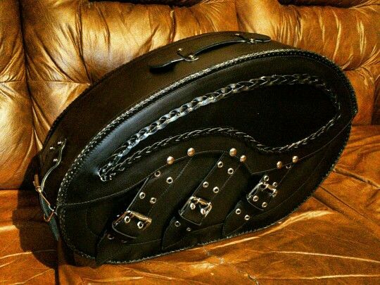 a black purse sitting on top of a brown leather couch with rivets and chains