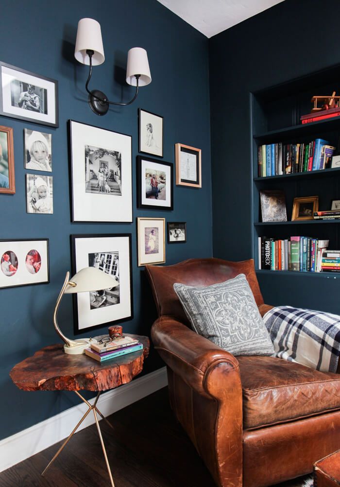 a living room with blue walls and pictures on the wall, two leather chairs in front of them