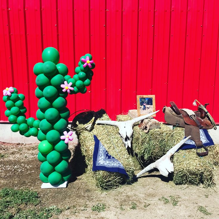 some fake animals are sitting in hay next to a red wall and a green cactus